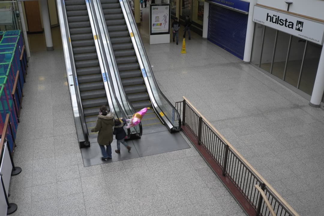 Photo of a girl with a baloon going up an escalator