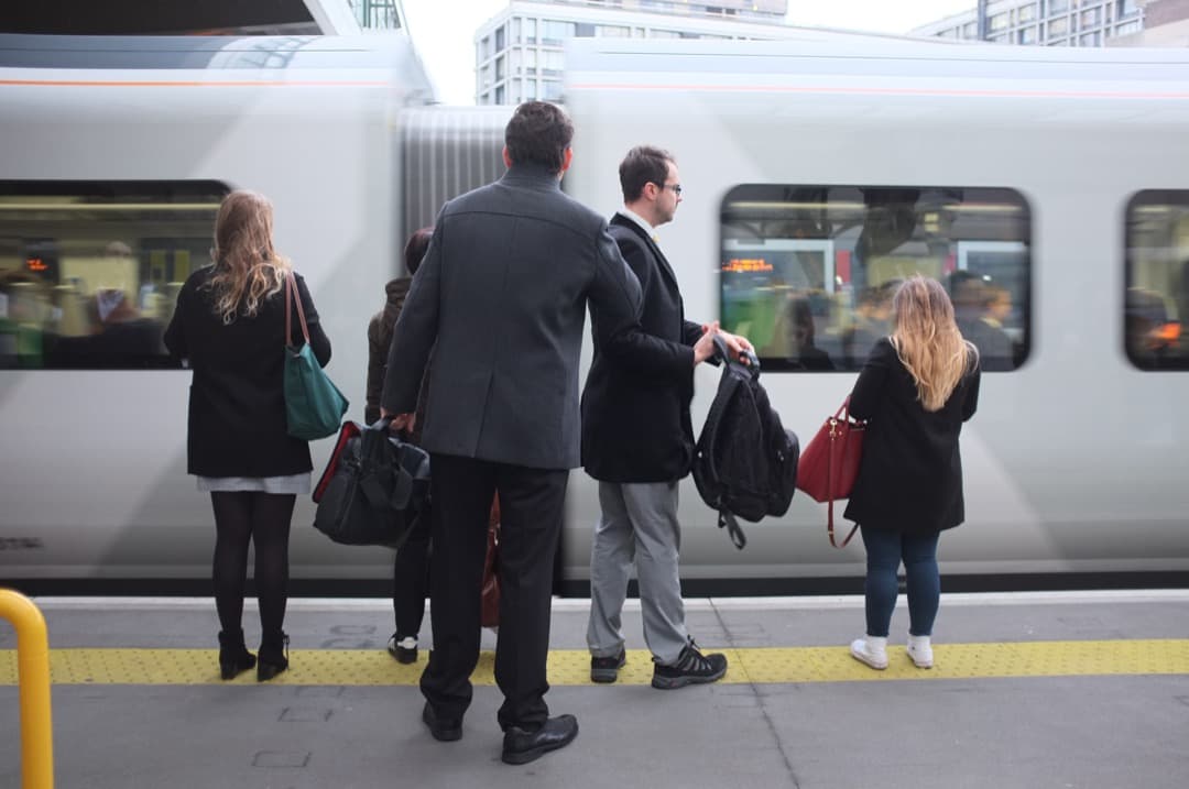 Photo of commuters getting ready to board an arriving train